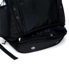 Open black backpack with a separate bottom compartment housing a pair of black sneakers. The compartment features ventilation eyelets, and the bag has hexagonal-patterned fabric with adjustable straps.