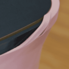 Close-up of a pink sleeve partially covering a dark blue object, likely a book or electronic device, on a wooden surface.