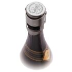A close-up view of a sealed dark glass bottle with a metal clasp and cap. The bottle has a gold and black label with decorative elements. The top cap features a logo with intricate design details.