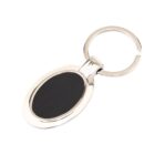A metallic oval keychain with a black center is placed against a white background. The keychain has a shiny finish and is attached to a round keyring.