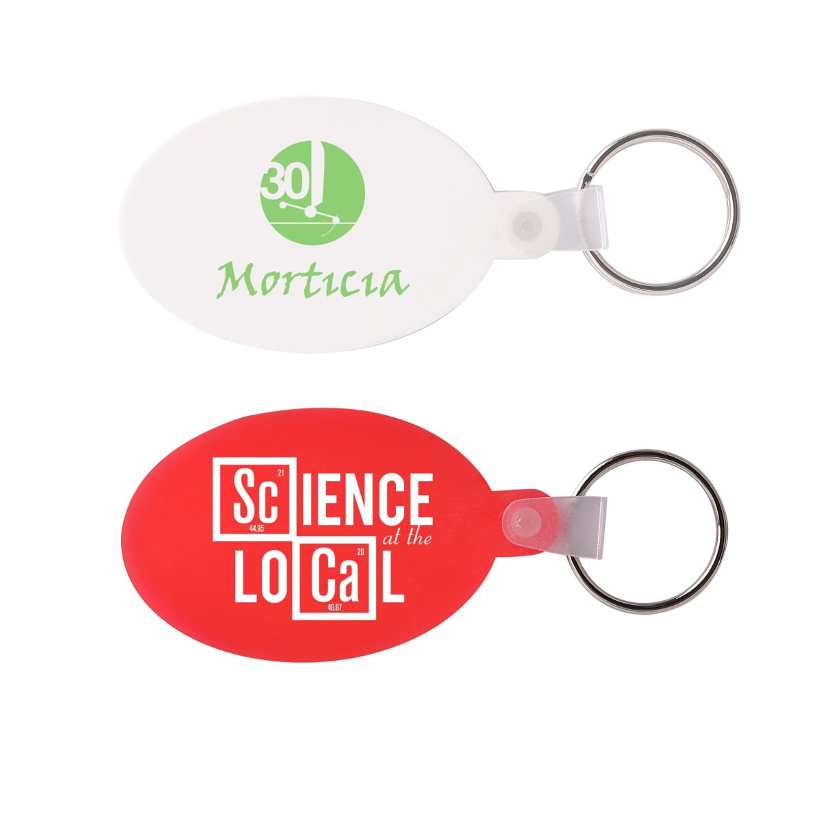 Two oval keychains: the top one is white with a green logo and text 30 Morticia. The bottom one is red with Science at the Local in white text, incorporating scientific symbols into the design. Both have attached metal rings.
