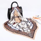 Silk scarf with a chain and polka dot pattern is elegantly draped over a black handbag. A magazine with colorful graphics is partially visible in the background on a white surface.
