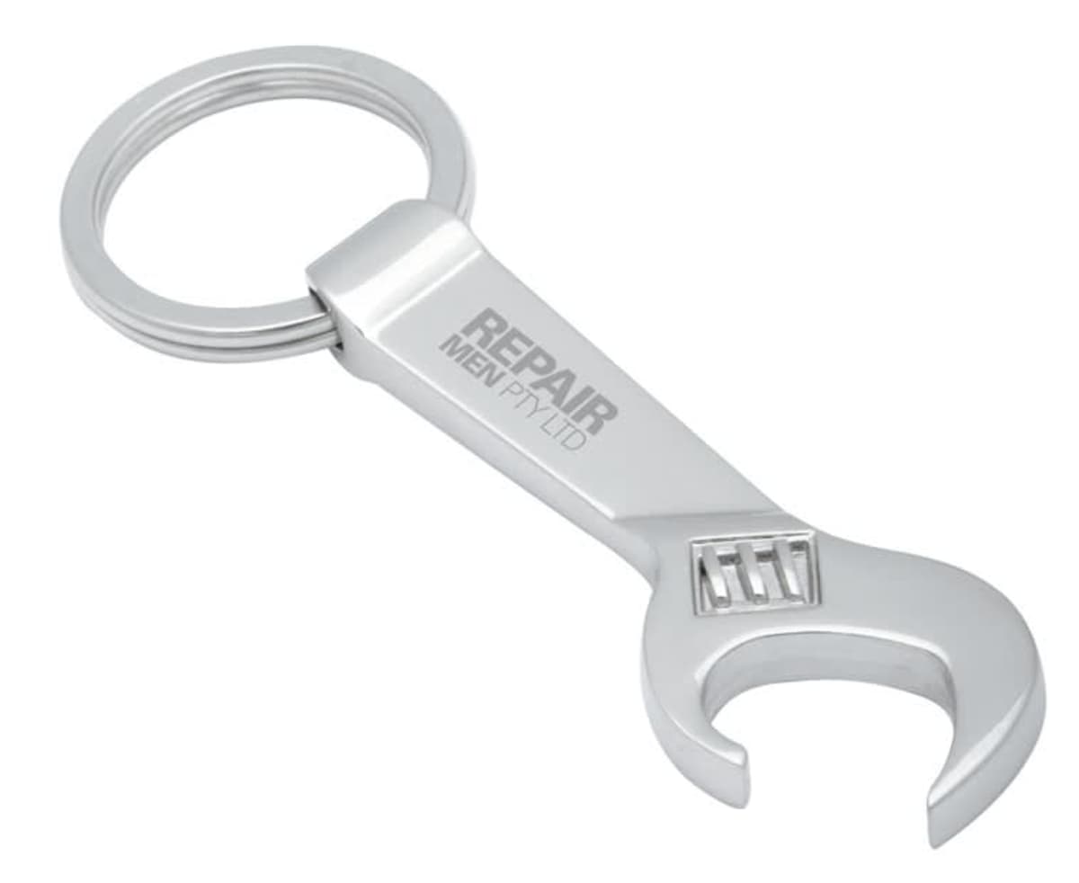 A silver keychain in the shape of a wrench with the words REPAIR MEN PR-LTD engraved on it. The opposite end features a keyring for attaching keys.