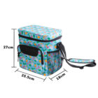 A colorful insulated lunch bag with tropical fruit patterns, including pineapples. It has front and side pockets, a shoulder strap, and dimensions labeled as 27 cm tall, 25.5 cm wide, and 18 cm deep.