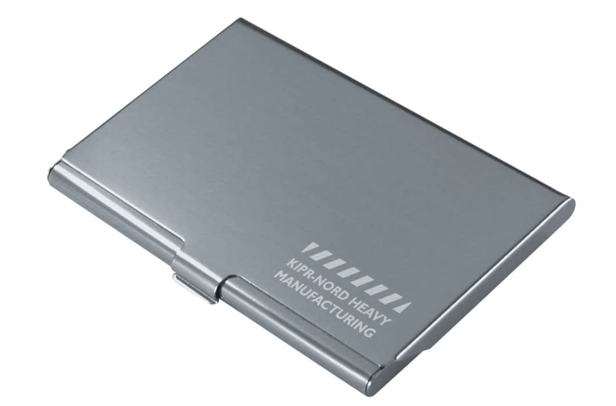 A sleek, silver metal business card holder is closed, with Kirin Nord Heavy Manufacturing engraved on the top.