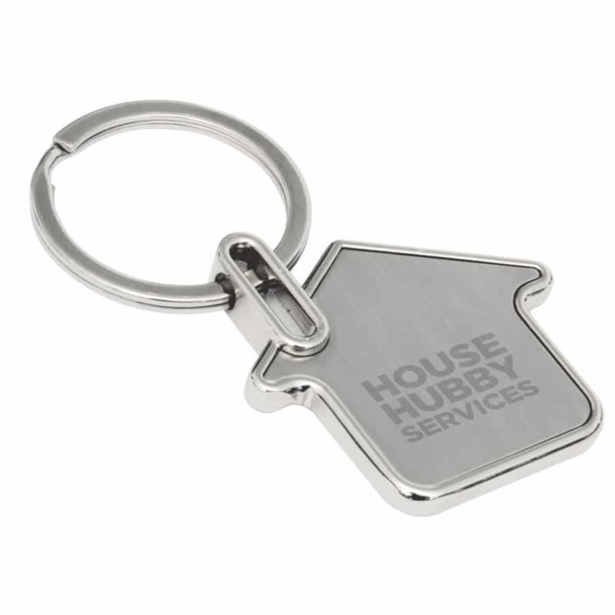 A silver keychain shaped like a house with the engraving HOUSE HUBBY SERVICES on its surface. The keyring is attached at the top corner of the house shape.