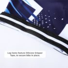 Close-up of cycling bib leg hems with black and white stitching visible. Beneath the hems is a label reading Leg hems feature Silicone Gripper Tape, to secure bibs in place. The fabric has a blue and white geometric pattern.