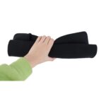 A person wearing a green sleeve is holding a rolled-up piece of black material, possibly a mat or fabric, against a white background.