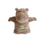 A plush hippopotamus hand puppet with outstretched arms, featuring a light brown body and pink inner ears. It has a logo with a green background on its belly. The puppet is isolated on a white background.