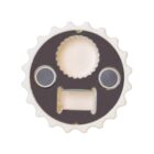 A round, gear-like object resembling a face with two circular eyes, a gear-shaped nose, and a rectangular mouth. It has a metallic appearance with a white outer edge.
