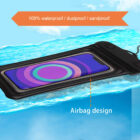A waterproof phone pouch floating on water, with a smartphone inside displaying a colorful screen. Text on the image reads 100% waterproof/dustproof/sandproof and Airbag design. The water has a clear, blue appearance.
