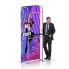 A smartly dressed man stands next to a display stand featuring a woman in workout attire. The backdrop includes neon lights and the text WILL IS POWER with smaller text advertising smart sportswear.