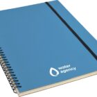 A blue spiral notebook with a black elastic band and the water agency logo featuring a stylized water droplet on the cover.