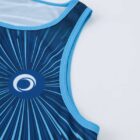 Close-up of a blue tank top with a circular design at the shoulder, featuring radiating lines in shades of blue, resembling rays. The design includes a white circular emblem at the center. The background is plain white.