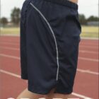 Person wearing navy athletic shorts standing on a running track. The shorts have reflective stripes. The words BOCINI and SPORTS are displayed in the image. Background includes blurred trees and field.