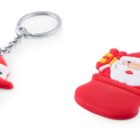 Two festive keychains are shown: one shaped like a snowman wearing a red and green scarf, and the other shaped like Santa Claus holding a small present and peeking from a red chimney. Both are attached to silver key rings.