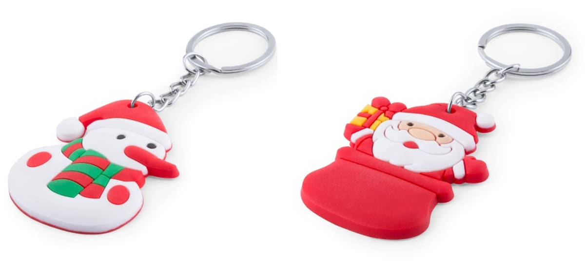 Two festive keychains are shown: one shaped like a snowman wearing a red and green scarf, and the other shaped like Santa Claus holding a small present and peeking from a red chimney. Both are attached to silver key rings.