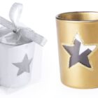 Two candle holders: one silver with a cutout star design in a box with a silver ribbon, and one gold with a similar star cutout. The star cutouts reveal the interior, adding a festive touch.