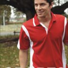 A man is outdoors wearing a red and white polo shirt with the BOCINI logo visible in the top left corner. He is smiling and walking on a grassy area with a large tree in the background. The word SPORTS is written at the bottom.