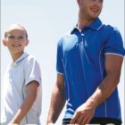 Two people in athletic polo shirts walking outdoors with a blue sky background. The person on the left wears a white shirt, and the person on the right wears a blue shirt. The word SPORTS is prominently displayed at the bottom.