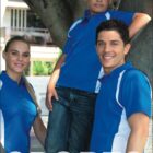 A woman, man, and a boy stand together outdoors, all wearing blue polo shirts with white accents. The man and woman smile, while the boy leans against a tree, resting his arm on the mans shoulder. The word SPORTS is at the bottom.