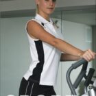 Person exercising on an elliptical machine, wearing a sleeveless white and black sports top and black shorts. The word SPORTS is written at the bottom, and BOCINI is at the top.