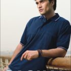 A person leans against a wooden railing wearing a navy blue polo shirt. The background is a hazy sky. The word CASUAL is written at the bottom, and the logo BOCINI is at the top left.