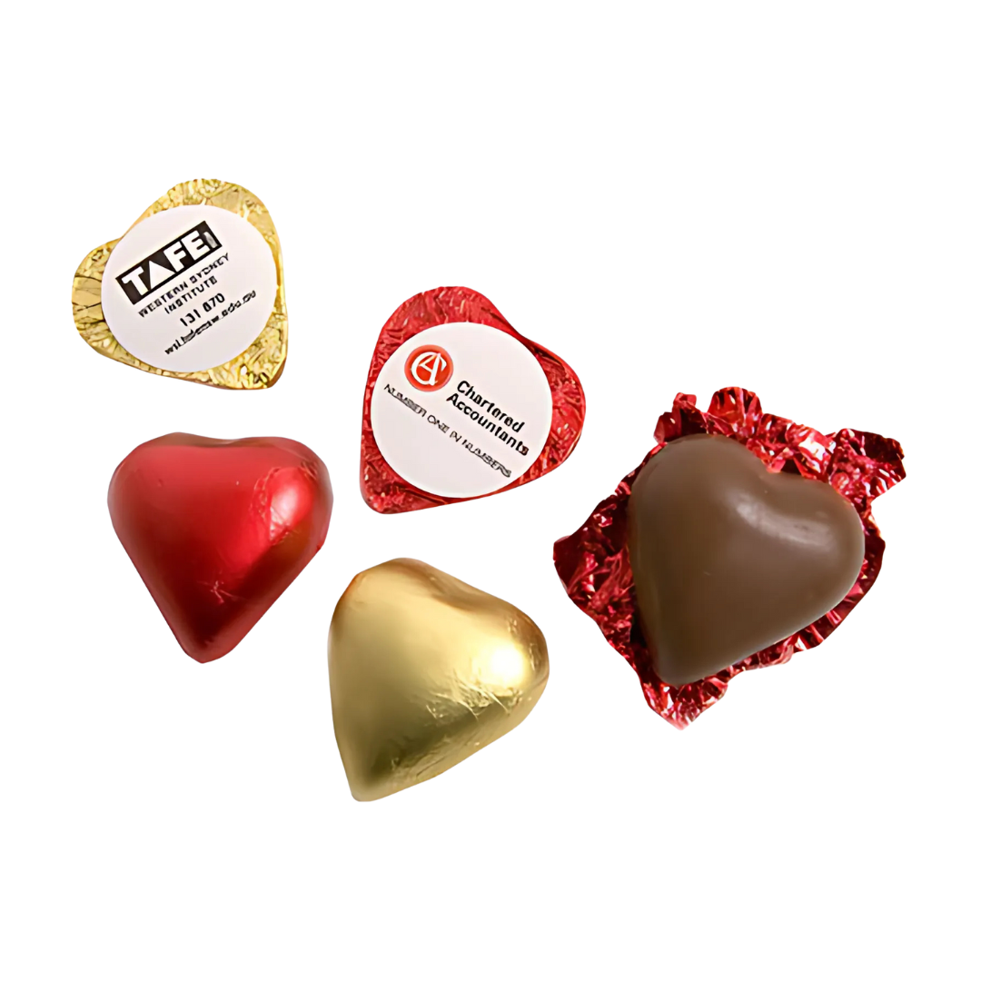 Five heart-shaped chocolates, some with custom red and gold foil, others unwrapped, display labels: TAFE Hunter Institute and Chartered Accountants. Product: Customised Chocolate Hearts.