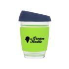 A transparent cup with a bright green silicone sleeve, featuring the Ice Cream Studio logo in black. It has a dark blue lid.