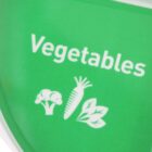 Green sign with the word Vegetables and white icons of broccoli, a carrot, and leafy greens.