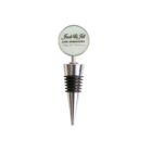 A silver wine stopper with a round top displaying the text Jack & Jill JJJC Associates, Happy 25th Anniversary. The stopper features black rubber rings and a sleek, tapered design.