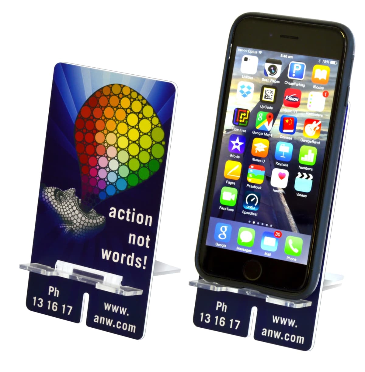 Two mobile phone stands display smartphones with colorful app icons on the screens. The stands feature a rainbow-colored parachute graphic and the text action not words! along with a website and phone number.