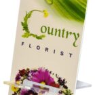 A colorful display stand for Country Florist featuring various vibrant flowers like daisies and pansies at the bottom, with green leaf and water droplet imagery at the top.