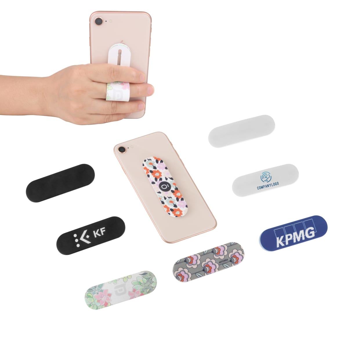 A hand holding a phone with a floral-patterned grip strap. Surrounding the phone are various grip straps in different designs, including plain, floral, and branded patterns with logos.