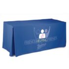 A blue tablecloth with the text Friends Helping Friends at Boscovs printed in white. The design includes abstract shapes of two people raising their arms, one with a heart symbol.