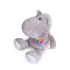 A soft, plush hippo toy sits upright. It is gray with white accents on its feet and ears. The hippos belly features a colorful embroidered logo that reads KIDS PLACE, and a small tag on its side says JUSTOT.