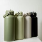 Four insulated water bottles with handles, featuring colors of dark green, light green, beige, and black, stand in a row on a white surface against a plain background.