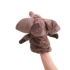 A person is holding up a plush brown elephant hand puppet against a plain white background. The puppet has large ears, a trunk, and is made of soft fabric.