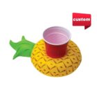 A red cup is placed in a yellow pineapple-shaped inflatable cup holder with green leaves. A red label with custom in white text is in the top right corner.