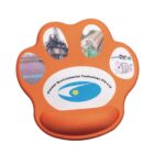 An orange paw-shaped mouse pad with an ergonomic wrist rest features the Pioneer Environmental Technology Pte Ltd logo in the center. Surrounding images show industrial and environmental scenes, including a facility and water treatment visuals.