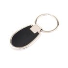 A silver metal keychain with an oval black center, attached to a circular keyring. The keychain has a sleek, modern design with a shiny finish, resting against a plain white background.