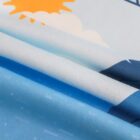 Close-up of a folded fabric featuring a bright sun, white clouds, and blue sky. The fabric has a smooth texture with a playful, colorful design, suggesting a cheerful theme.