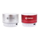Two portable Bluetooth speakers, one silver and one red, with the word COMPANY on each. Both have control buttons and ports on the base, displayed against a white background.