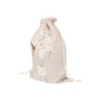 A beige drawstring bag adorned with light pink cherry blossom prints and a butterfly. The bag is slightly cinched at the top, with strings on both sides.