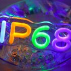 Neon-style glowing letters and numbers spelling IP68 in orange, green, and purple, surrounded by vibrant blue and purple lighting effects. The design appears above a reflective, liquid-like surface with scattered ice-like cubes.