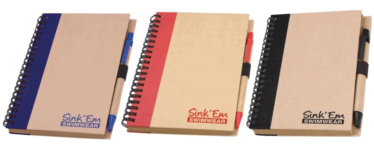 Three spiral-bound notebooks with pens attached. Each notebook has a colored stripe: blue, red, and black. The cover reads Sink Em Swimwear with the logo matching the color of the stripe.