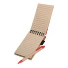 A small, spiral-bound notebook with brown cardboard covers is open, showing lined pages. A wooden pen with a red tip is placed on the notebook. The notebook has elastic bands to hold the pen in place.