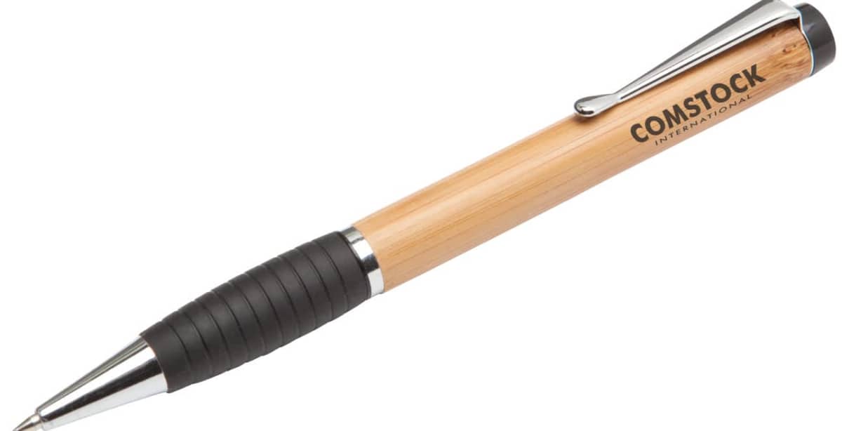 A ballpoint pen with a wooden barrel and metal clip, featuring the logo Comstock International printed on the side. The pen has a black rubber grip for comfortable handling.