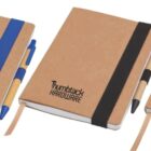 Three brown notebooks each have an elastic band and pen holder in blue, black, and red, respectively. The notebooks feature the text Thumbtack Hardware on their covers.