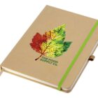 A beige notebook with a multicolored leaf design on the cover featuring reds, yellows, and greens. It has the words The Food Supply Co. printed below the leaf. The notebook has a green elastic band and a brown ribbon bookmark.